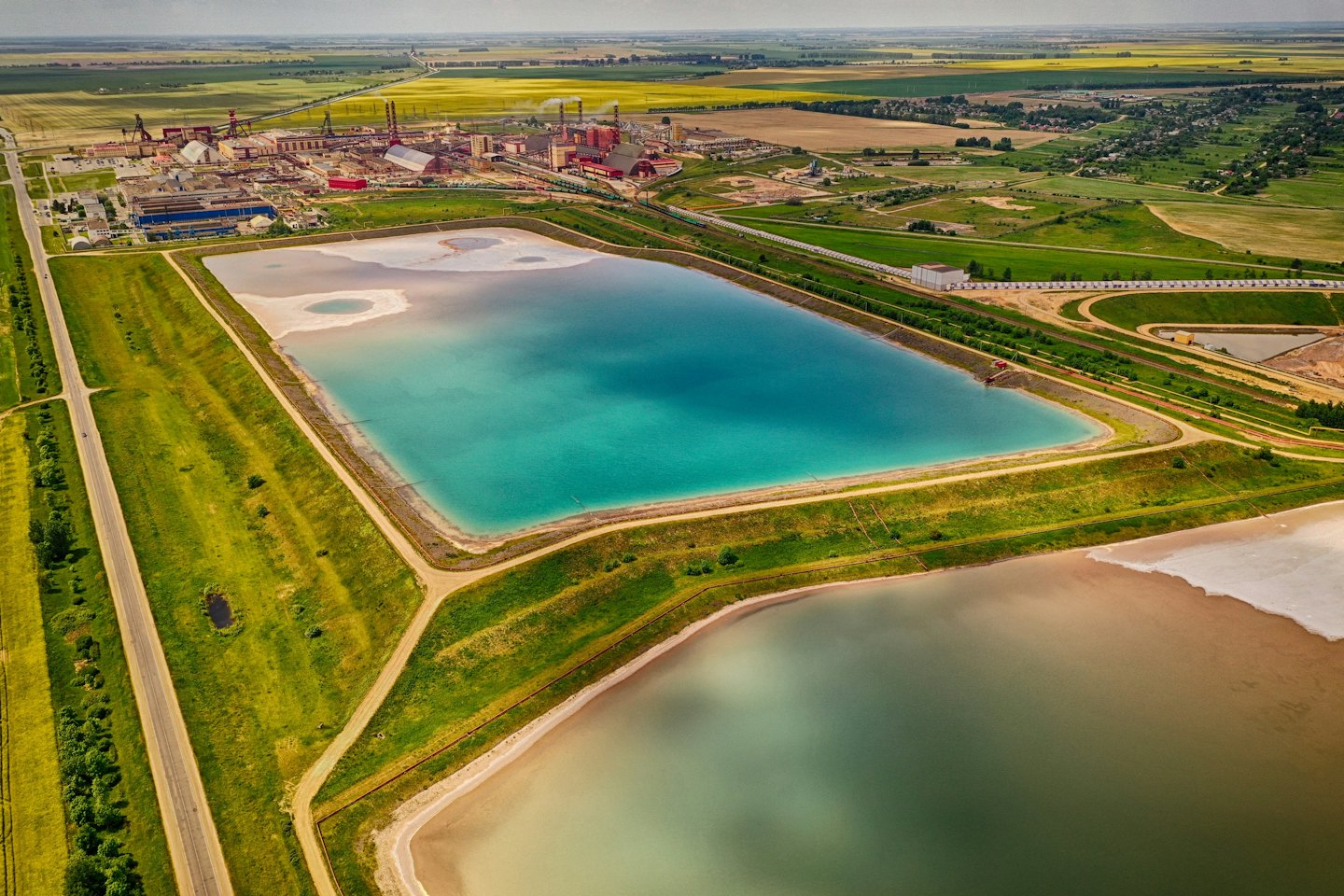 Aerial view of industrial ponds next to green farmland.