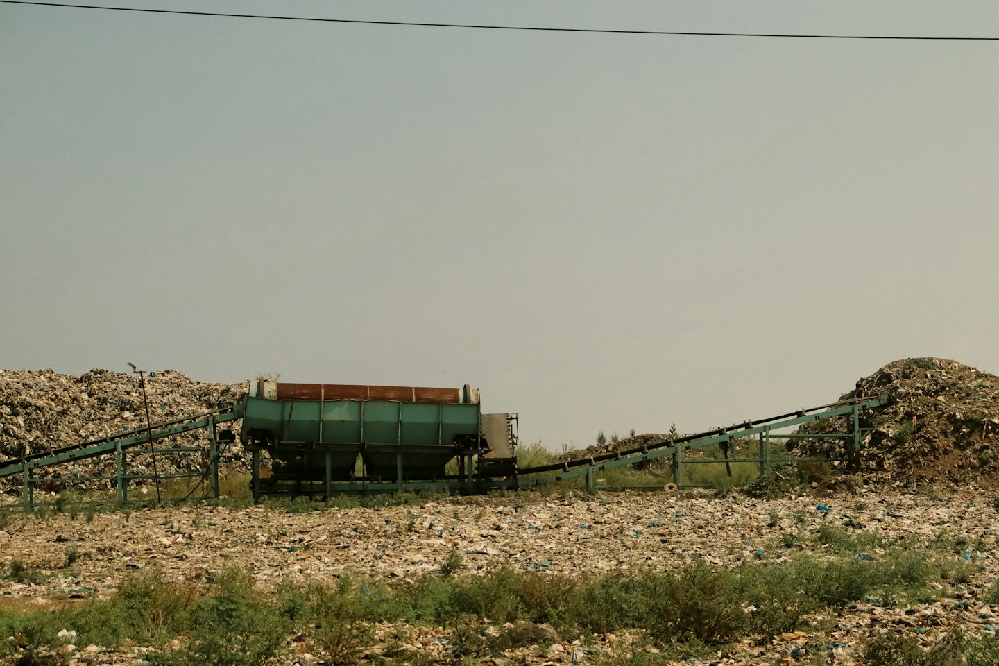 A teal industrial machine processes waste at a large facility.